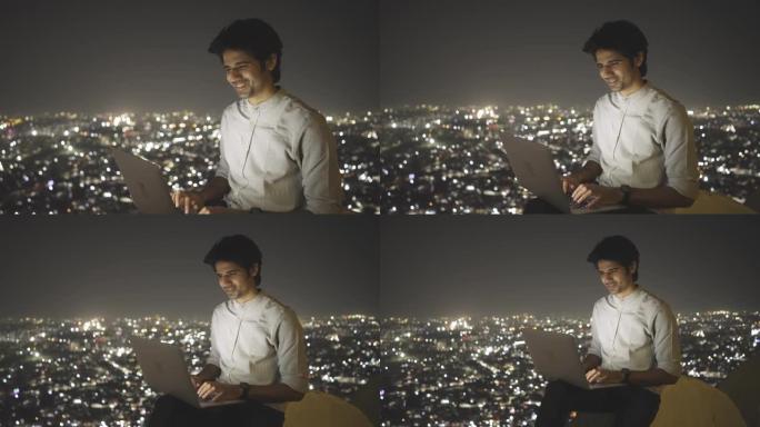 一位男性企业家正在为照明的夜景市景制作笔记本电脑