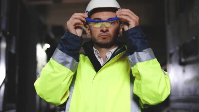 专业的重工业工程师工人穿着制服，戴着眼镜和安全帽在钢铁厂看着相机。站在金属建筑制造商中的高加索工业专