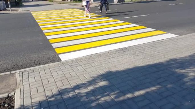 4k视频，两个行人过马路上新的人行横道黄白标记，生命安全，运输概念