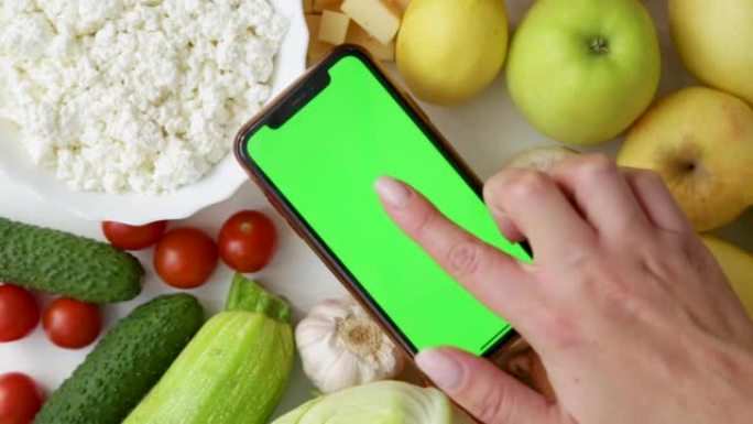 带有chromakey的手机躺在食物中，手在屏幕上发出咔嗒声和滑动声