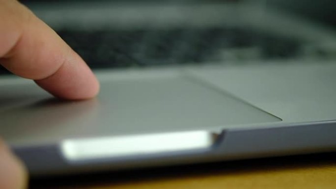 男士手指在工作时使用笔记本电脑触摸板的特写慢动作，使用电脑