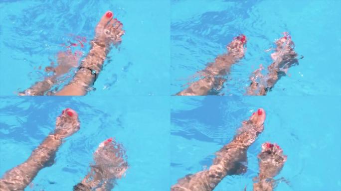带有红色指甲油的雌性脚在水中移动，飞溅