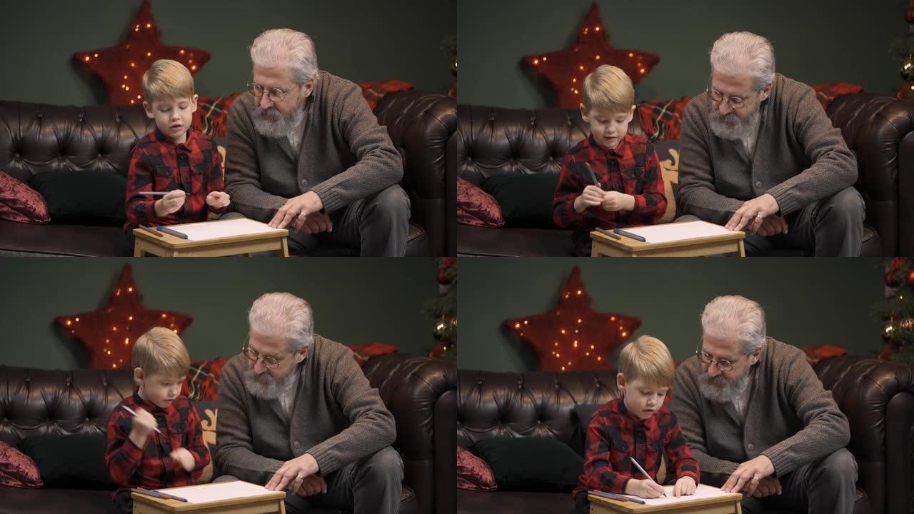 小男孩用毡尖笔画了一幅喜庆的画。祖父和孙子坐在靠近发光圣诞树的装饰房间的沙发上。家庭度假概念。平安夜