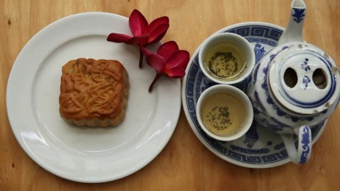 自然光下有月饼和红花的中国茶具，背景
