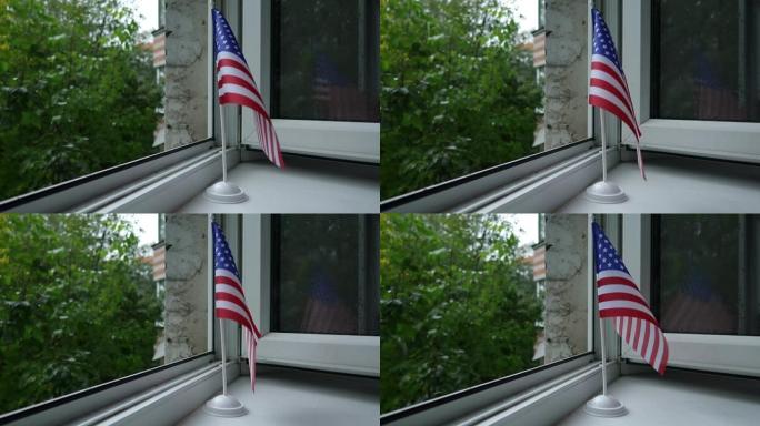 美国国旗立在架子上 窗户上，在风中飘动。