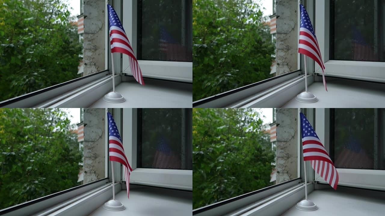 美国国旗立在架子上 窗户上，在风中飘动。