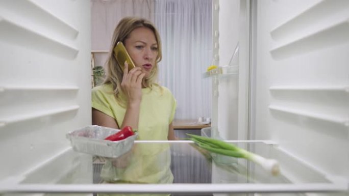 网上杂货店购物送货。女人打开冰箱寻找食物，并使用现代在线食品商店服务将营养带回家。从冰箱里看。特写。