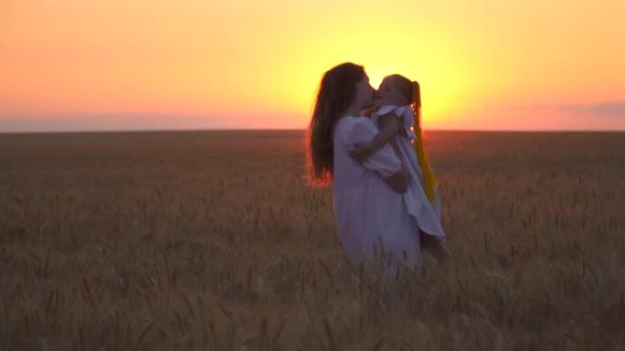 妈妈和女儿在野外玩得很开心。日落时分，妈妈和女儿快乐。两个女孩姐妹正在麦田里散步。自然界中的人。自由