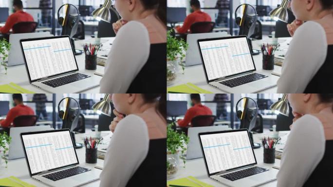 白人妇女坐在办公桌前观看笔记本电脑屏幕上的编码数据处理