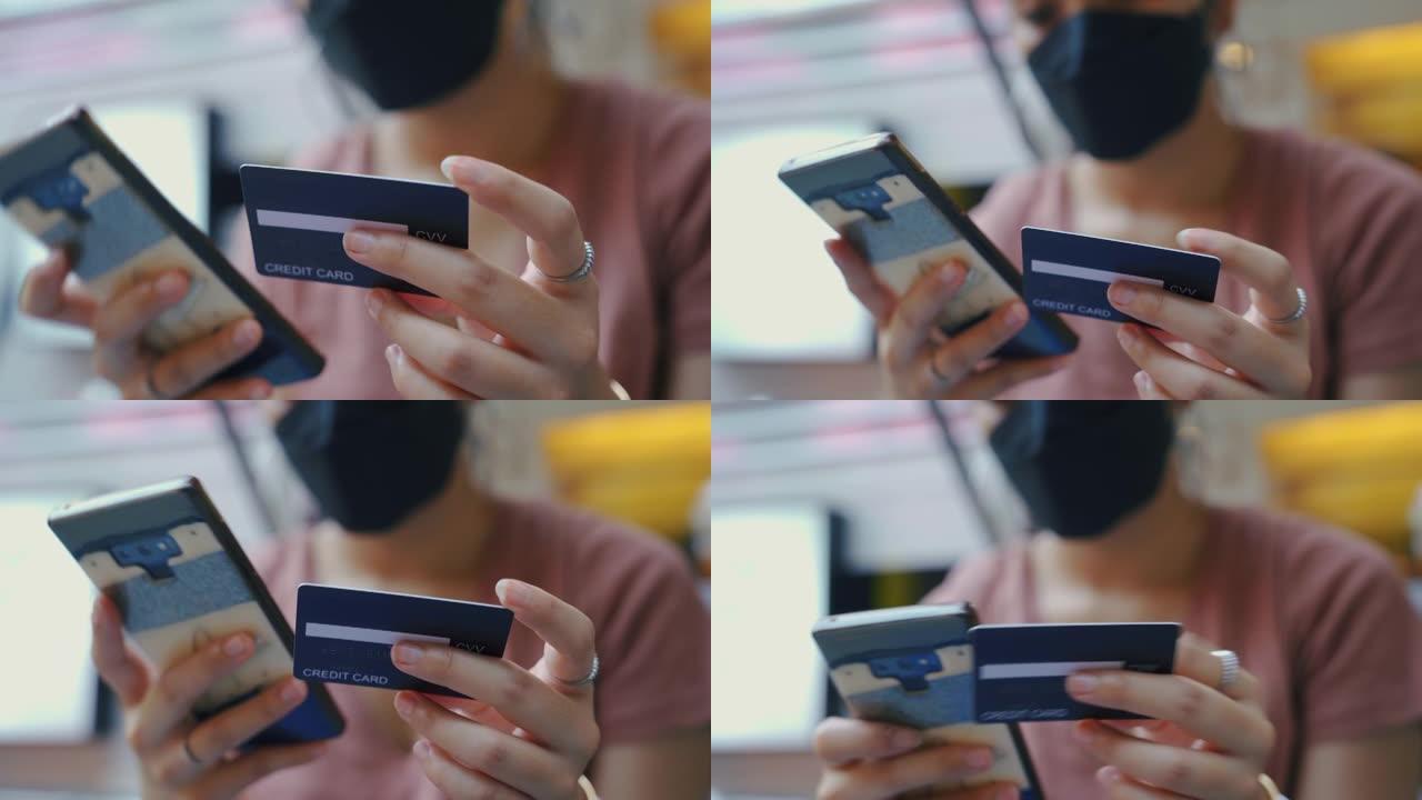 亚洲妇女在使用信用卡进行在线交易时使用手机。