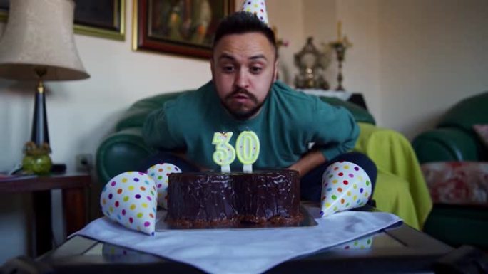 快乐的人在家里庆祝自己的30岁生日时，吹着生日蛋糕上的蜡烛