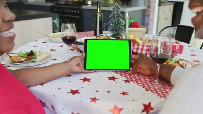 戴着圣诞老人帽子的微笑的非洲裔美国夫妇进行平板电脑圣诞视频通话，绿屏