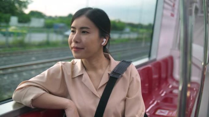 年轻迷人的女人戴着无线耳机，在火车上旅行时听音乐
