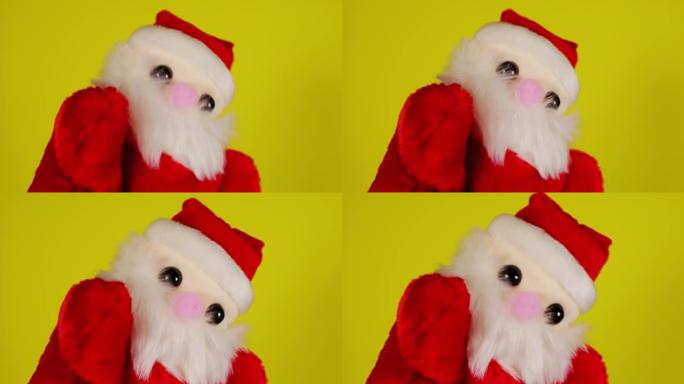 手上点头的圣诞老人毛绒玩具。黄色背景上圣诞老人木偶的特写。布袋戏的概念和即将到来的新年假期