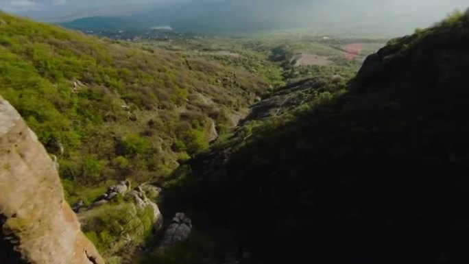 山岩之间的极端飞行。射。在山坡上的岩石地层快速飞行。像翼服一样在绿色山脉的岩石斜坡上飞翔