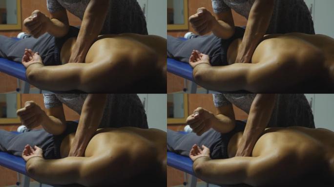 专业按摩师在客厅用肘部按摩运动员的臀部。经过艰苦训练后，按摩师放松和振兴运动员的肌肉。健康生活方式的
