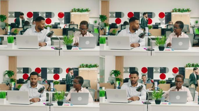 两名极具吸引力的非洲工人在一间灯火通明的大办公室里，他们在餐桌旁互相帮助工作和交谈。阿里·阿列克谢迷