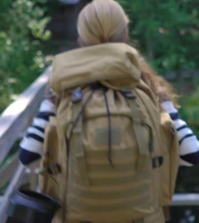 一个背着大背包的年轻女子徒步旅行了一条旅游森林小径