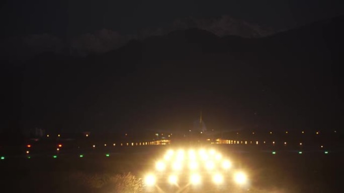 飞机在夜晚的黑暗中接近并降落在机场