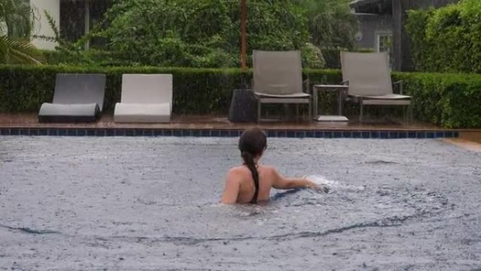 大雨时在游泳池里洗澡，女人享受假期