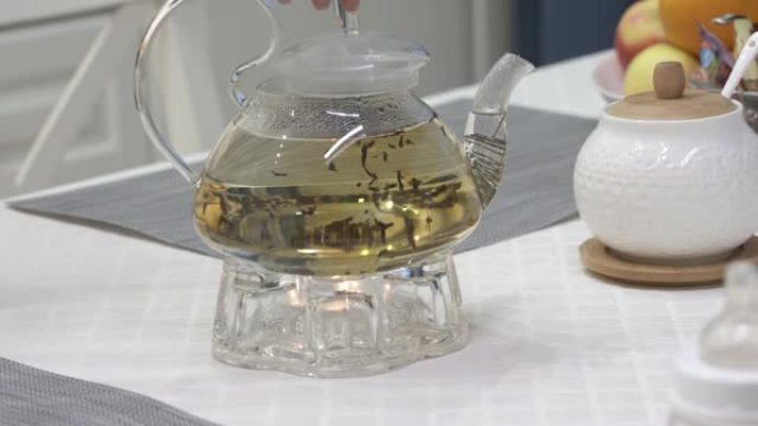在厨房用茶壶和茶灯蜡烛在取暖器上准备茶。慢动作用散叶茶泡茶。早餐时间。