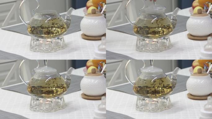 在厨房用茶壶和茶灯蜡烛在取暖器上准备茶。慢动作用散叶茶泡茶。早餐时间。