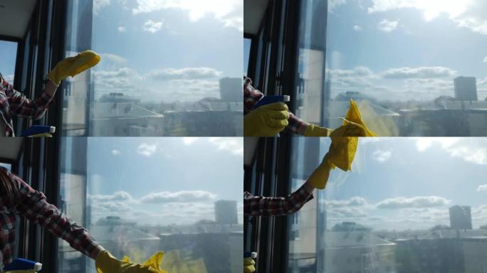 戴着黄色手套的手洗窗户。在脏窗户上喷洒窗户清洁剂。弹簧清洁