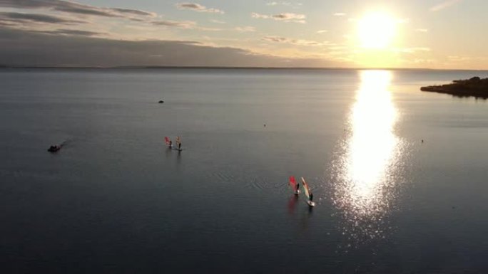 人们在日落时在海上滑浪风帆，鸟瞰图