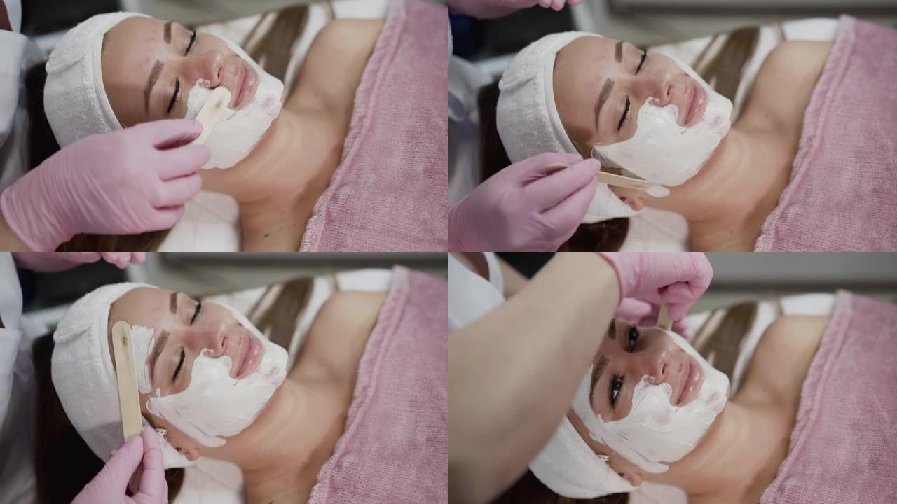 美容院女性脸上抹上抹刀白色面膜的水疗程序