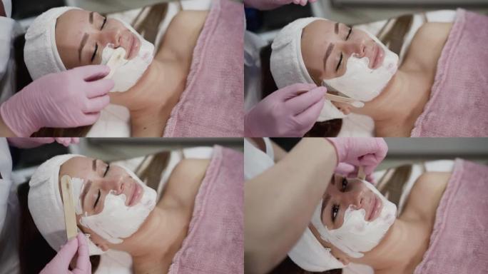 美容院女性脸上抹上抹刀白色面膜的水疗程序