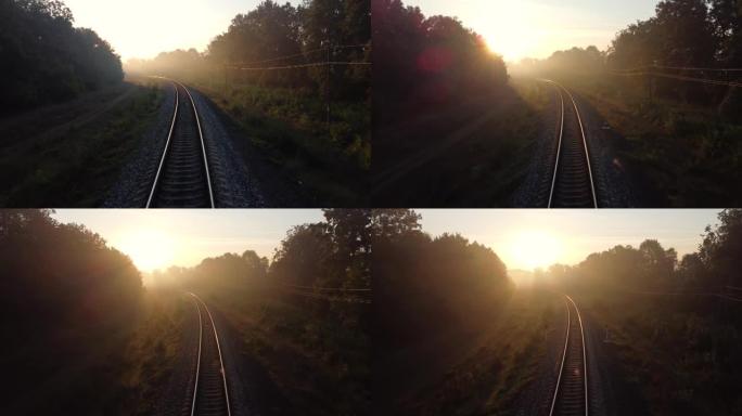火车道路上布满了晨雾，阳光穿过树枝和长长的阴影。