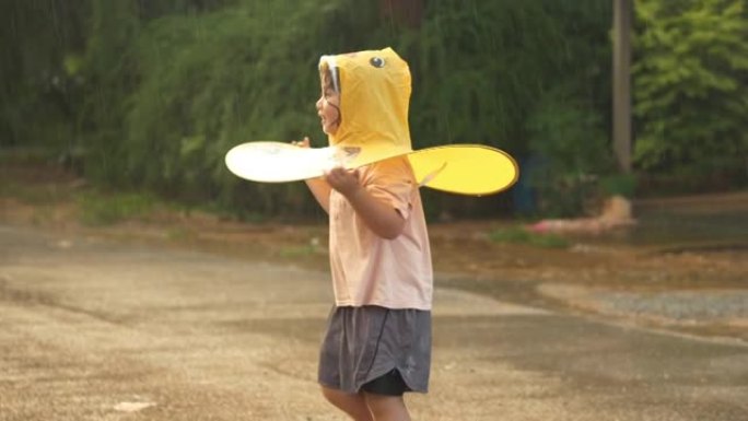 亚洲小女孩在雨中玩水。