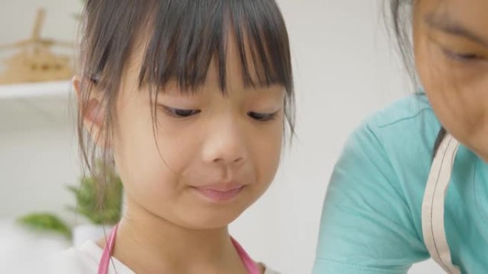 亚洲女孩舔她的手指测试糖的甜味，看着她的妹妹。