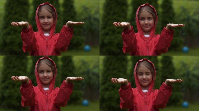 快乐的小女孩在雨中微笑。孩子热爱自然，幸福自由。玩水滴雨的孩子。儿童在下雨的夏日在户外玩耍。穿着红色