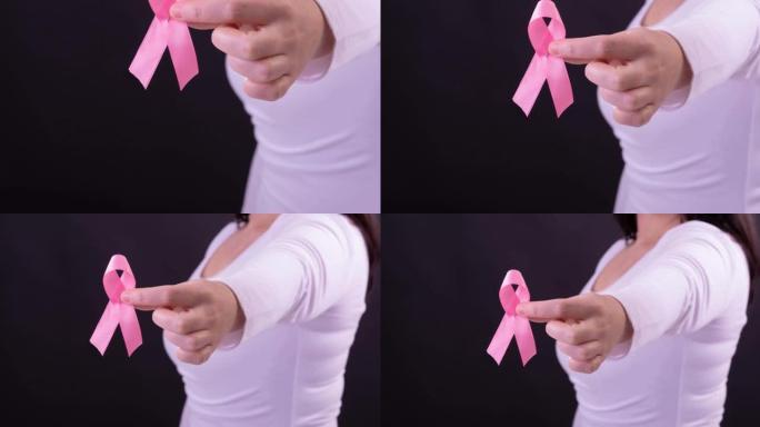 白人妇女手持粉红癌症意识丝带，黑色背景的中段视频