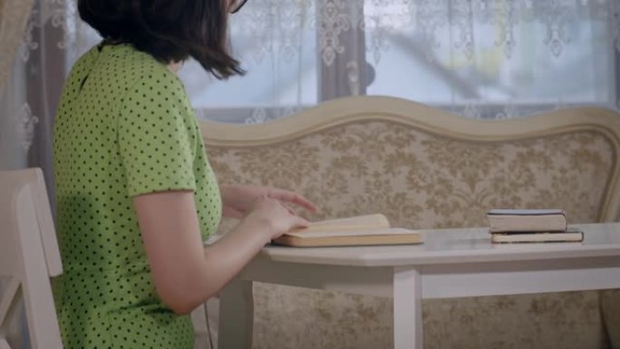 一个女孩坐在桌子旁看书的侧视图