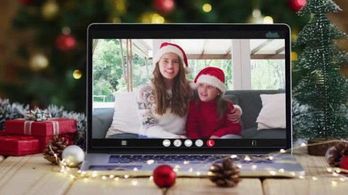 快乐的母女在笔记本电脑上进行视频通话，带有圣诞节装饰和树木