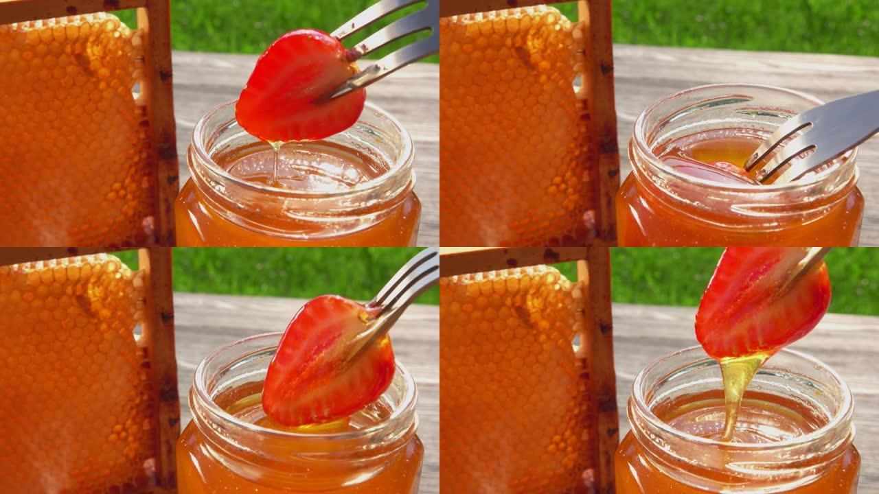 叉子上的成熟草莓的特写镜头蘸上美味的蜂蜜