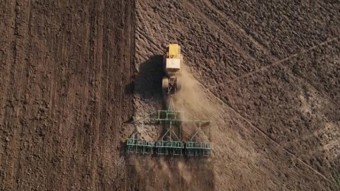 带有耙的重型农业机械使土壤松动，为在农村地区播种小麦做好准备，俯视图，从高处用无人机射击