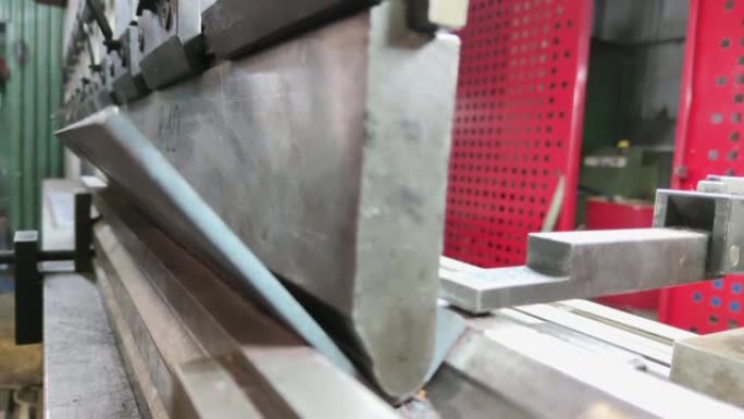 在折弯机上弯曲厚金属片，特写。折弯机操作员弯曲钣金产品。一名工人在金属加工厂工作。