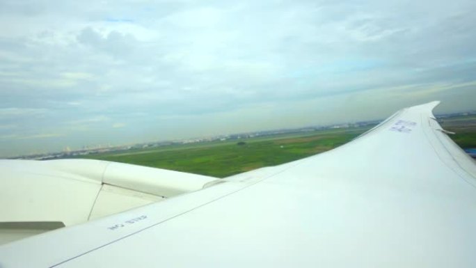 在阳光明媚的日子起飞时，透过飞机的窗户，郁郁葱葱的风景，飞机的机翼和涡轮机。