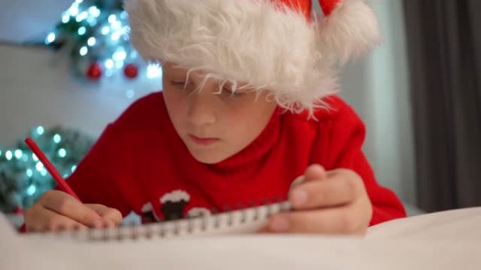 戴着圣诞老人帽子的可爱的小男孩写信给圣诞老人买礼物