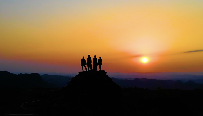 日落时分一群青年站在山顶看日落户外旅游光