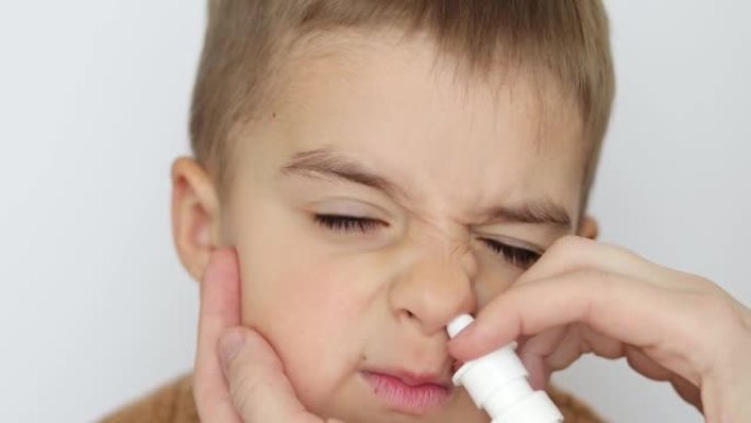 母亲在鼻子里喷她男孩的药，滴鼻子。妇女使用鼻喷雾剂为儿童。流鼻涕，感冒，流感，疾病，病毒。特写。