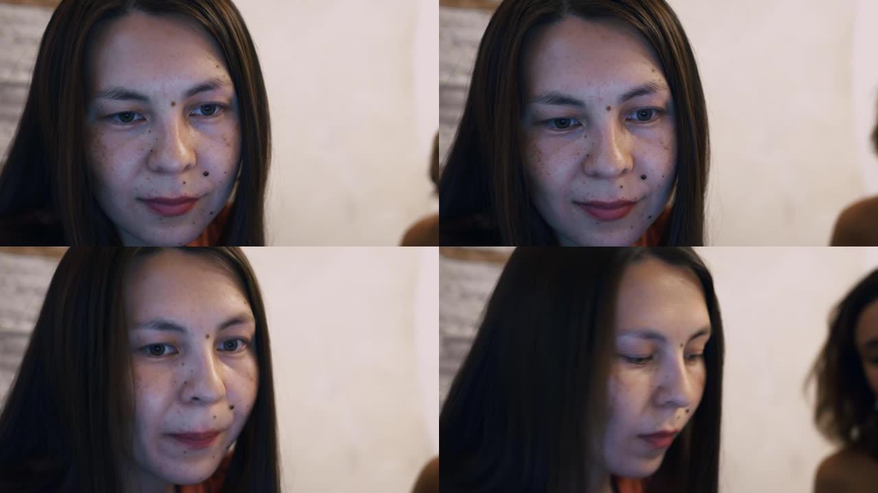 一个亚洲美女的特写脸，这个女人脸上有很多痣和雀斑。一个女人在家用电脑远程工作