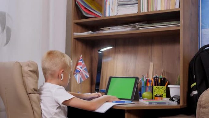 学龄前儿童男孩远程在线学习在家。绿屏。