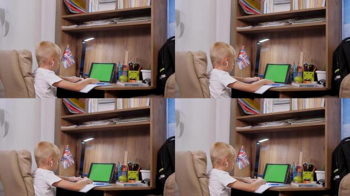 学龄前儿童男孩远程在线学习在家。绿屏。