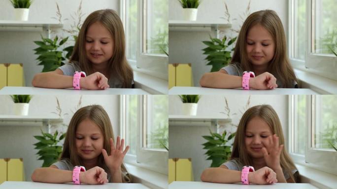 快乐的高加索小女孩使用儿童智能手表进行视频聊天。智能手表上的视频通话。儿童在室内使用智能手表，与朋友