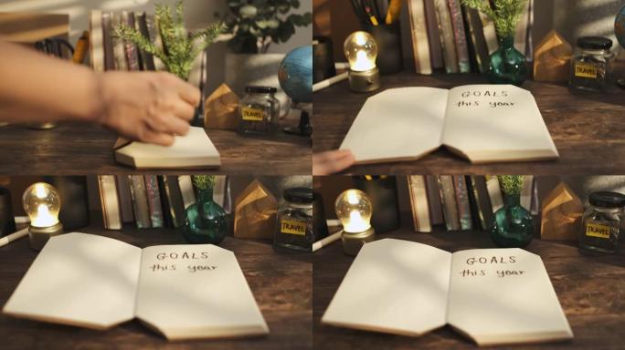 今年用手打开带目标的笔记本手写文字在家里的木头桌子上，早晨从窗户上晒出阳光。新年决议目标列表