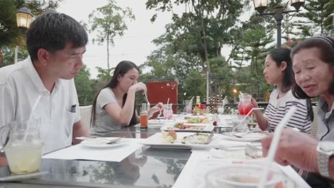 家庭团聚期间幸福家庭在餐厅吃晚饭的手持照片